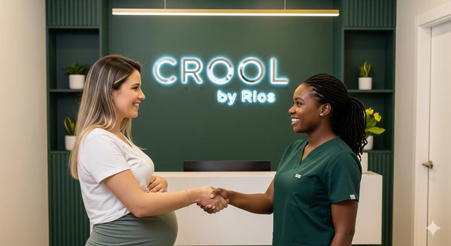 Uma mulher brasileira de 35 anos, loira e grávida, cumprimentando uma dentista mulher, negra de 30 anos em um consultório odontológico. A mulher grávida está de perfil e vemos a barriga dela. Ela está fazendo um acompanhamento odontológico preventivo para não ter gengivite na gravidez.