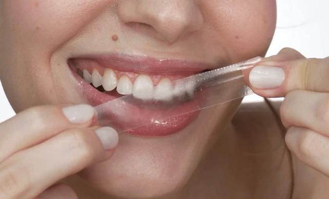 Mulher adepta do uso de fitas de clareamento dental.