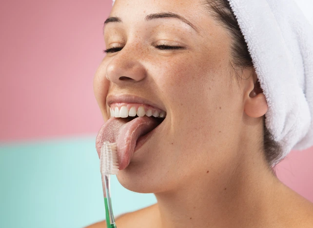 Mulher fazendo a higiene da língua.
