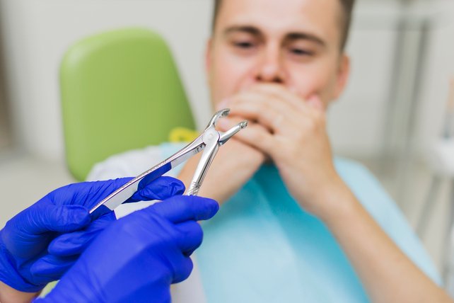 Dentista segurando um alicate para extrair o dente de um paciente.