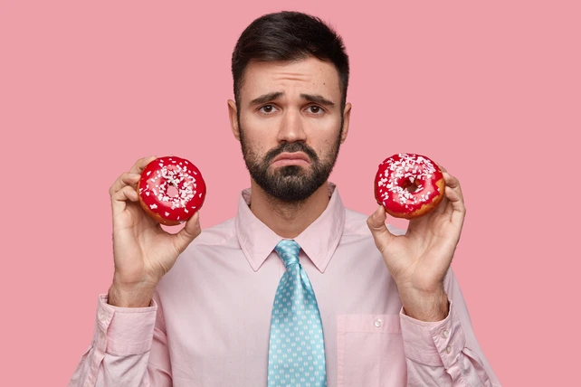 Homem triste segurando dois donuts.