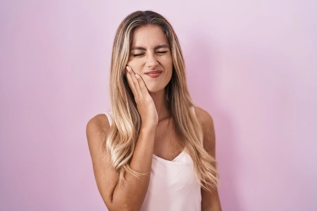Mulher loira com dor de dente.