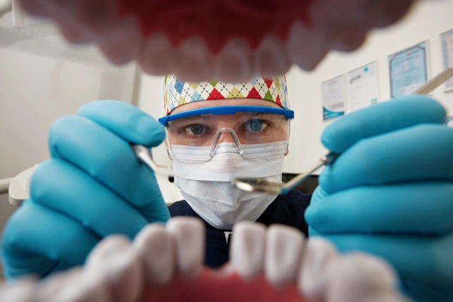 Dentista analisando dentro da boca do paciente.