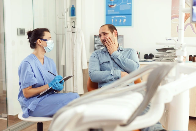 Homem com dor de dente na cadeira do dentista.